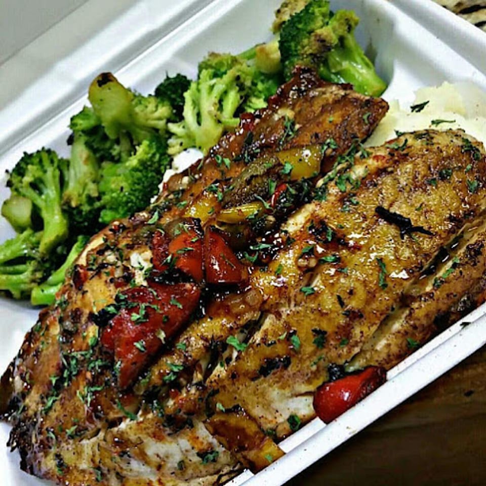 Cajun-style fish fillets with red and green peppers, served with mashed potatoes and broccoli.